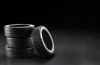 Four car tires on the asphalt on a black background, 3D rendering illustration.